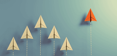 Several beige paper airplanes flying in formation with one red paper airplane taking a higher path